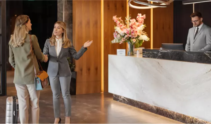 The picture shows two women at front desk of hotel asking for refund of their money due to a dispute