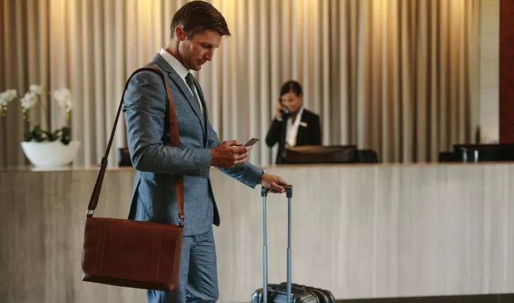 the picture shows a person standing in a hotel lobby in front of reception and waiting for his disputed nonrefund as he is not staying in the hotel due to some emergency.