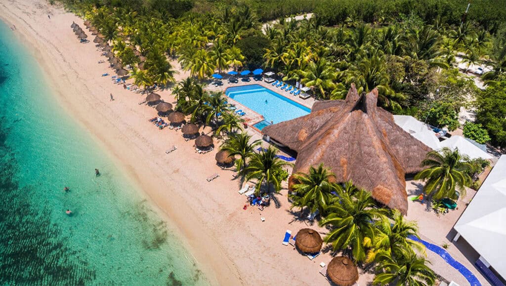 Aerial view of Nachi Cocom Beach Club in Cozumel, Mexico, captured by drone, showcasing the pristine beach, crystal-clear waters, and relaxed atmosphere, perfect for a day pass excursion.